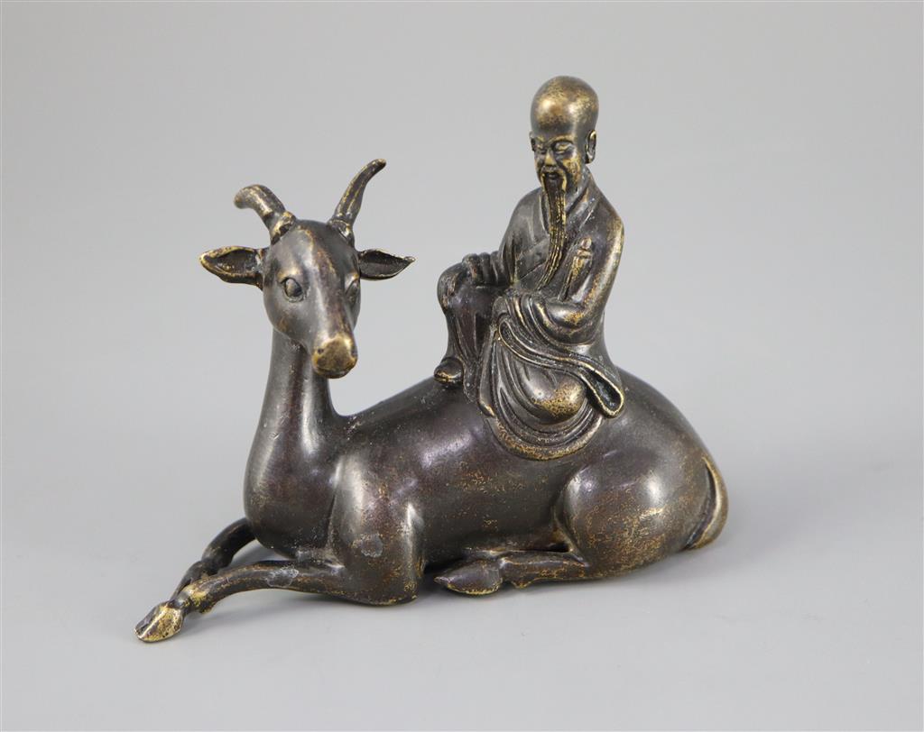 A Chinese late Ming bronze group of an immortal seated on a recumbent deer, 12.5cm long